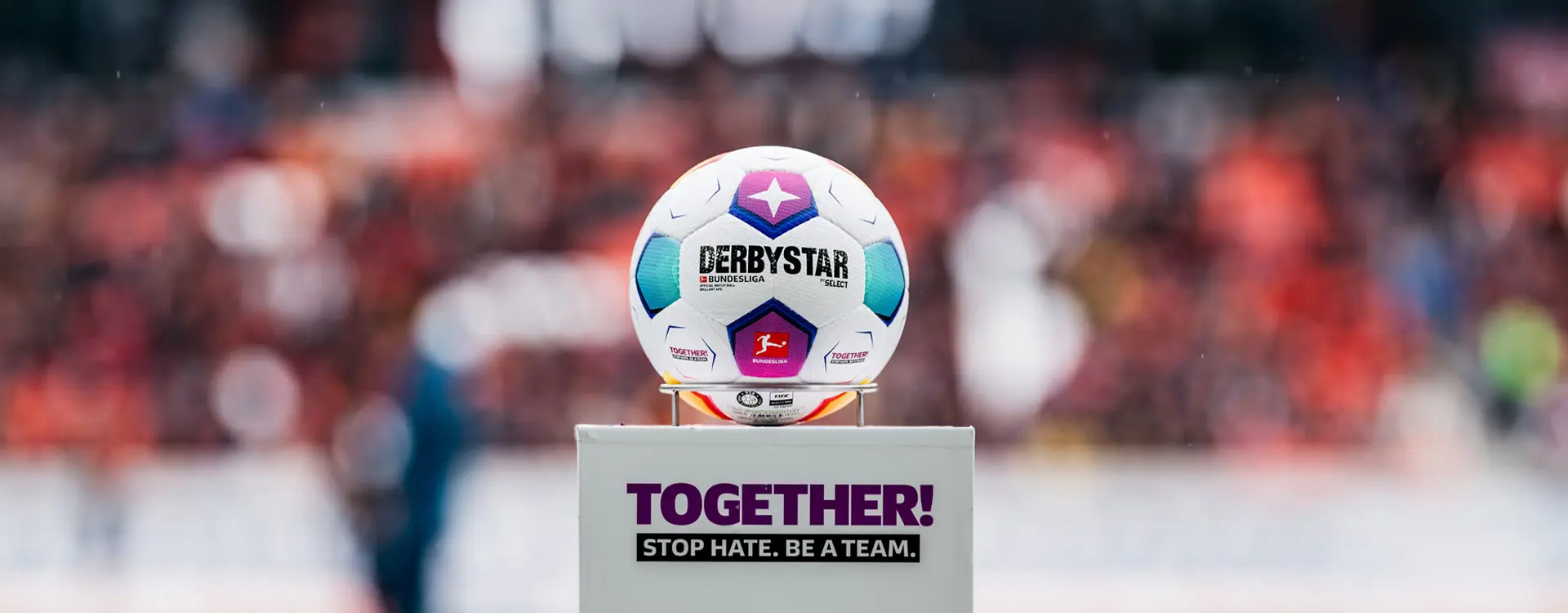 The image shows a trophy with a ball on top of it placed indoors, with what appears to be a sports team or group participating in a celebration. In the background, there are spectators visible behind a protective barrier, suggesting that this is a private event rather than a public match. The atmosphere looks festive and celebratory.
The text and imagery on the trophy indicate it may be related to a football (soccer) competition, specifically mentioning "Liga de Quito," which could imply an affiliation with a team from Ecuador named Quito or associated with that city's league. There are logos of what appear to be sponsors or organizers.
There is no visible text within the trophy itself, and the background is mostly out of focus with emphasis on the celebration. The photo seems to have been taken quickly without much attention given to the background, thus the rest of the environment isn't distinctly visible.