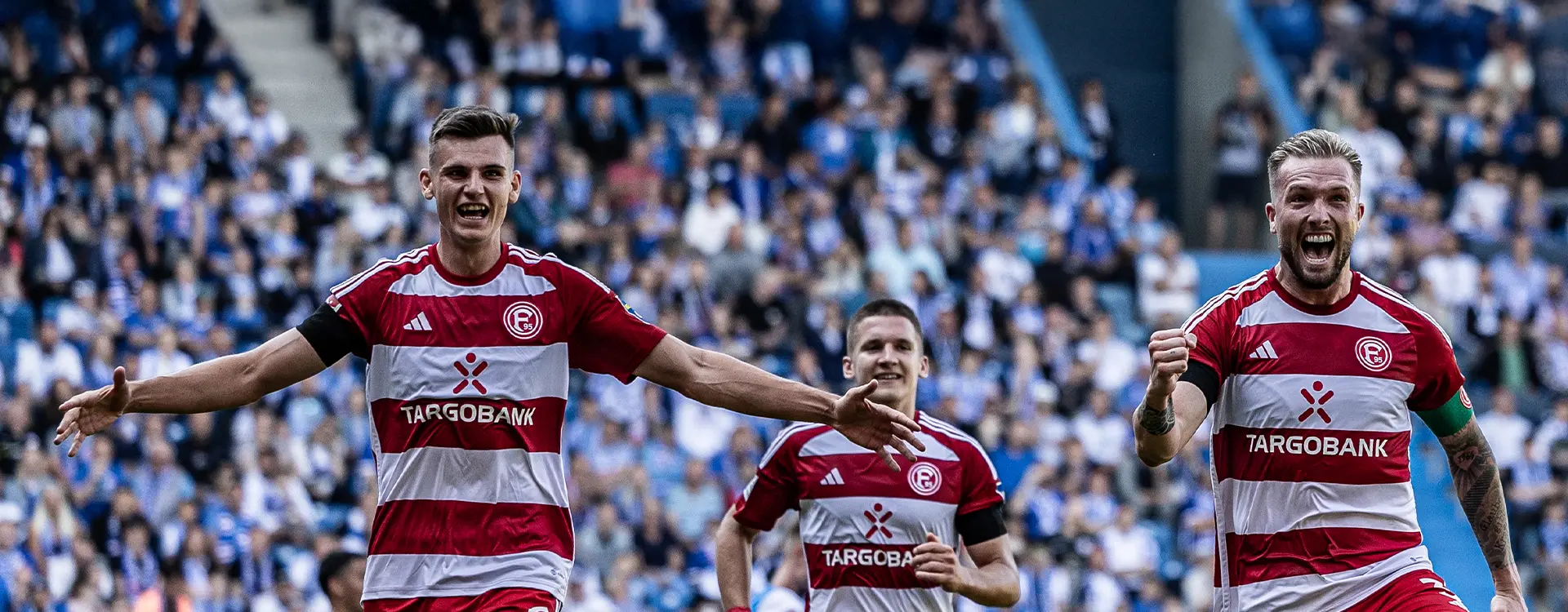 The image shows a sequence of four photos featuring two soccer players from different teams. Both players are in mid-action with expressive postures; their faces reflect intense emotions, which could be interpreted as frustration or disappointment. They appear to be at a professional football match, as indicated by the stadium seating in the background and the branding on the jerseys, suggesting they are playing for clubs associated with those brands. The presence of team coaches looking on indicates a moment from a competitive game. Without context, it's impossible to provide more specific details about the event or players involved.