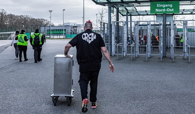 A man with the word ‘Crew’ printed on his shirt pushes a silver box. (Photo)
