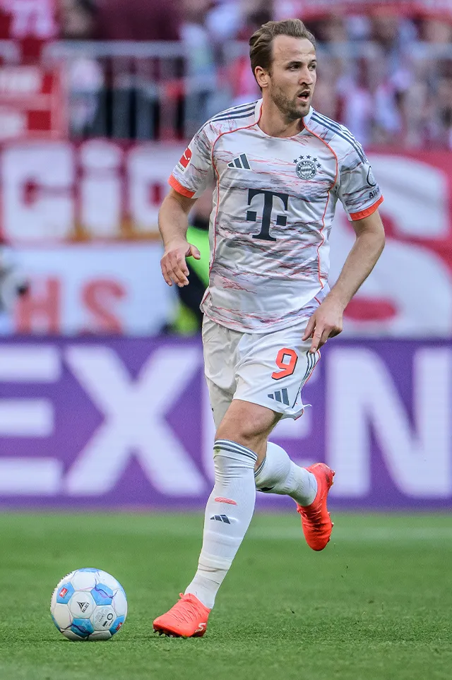 Harry Kane, wearing a white jersey and with the ball at his feet, scans the pitch. (Photo)